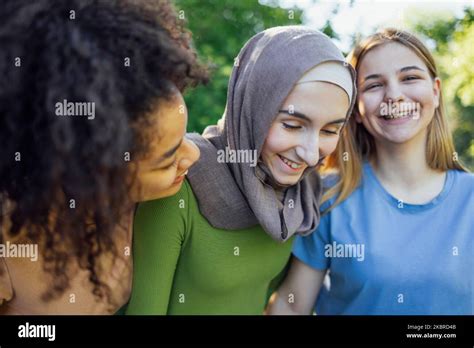 Multiracial young teen female friends walking in the park laughing and