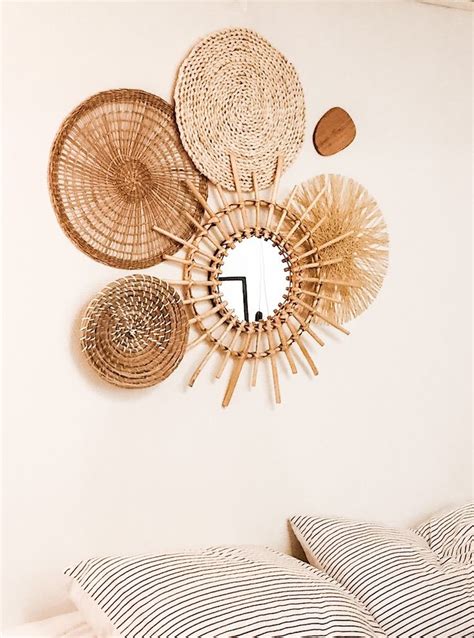 A Bed Topped With Pillows Next To A Mirror And Wall Mounted Wicker Art