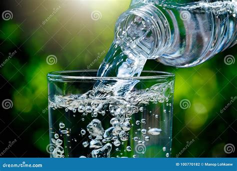 Close Up Of Water Flowing From Drinking Water Bottle Into Glass On