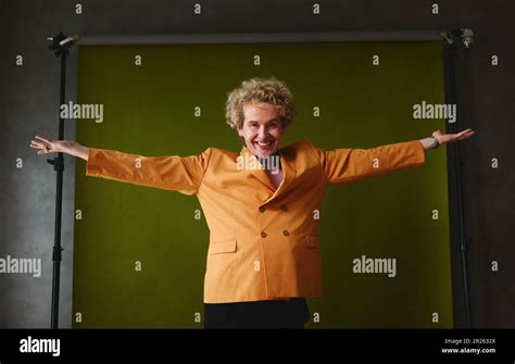 Portrait Of Gay Man With Arms Outstretched Against Studio Backdrop For Pride Month Stock Photo