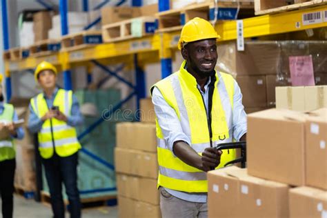 Black Male Warehouse Worker Pulling A Pallet Truck Middle Aged African