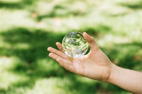 Free Photo Close Up Of Hand Holding Transparent Sphere At Outdoors