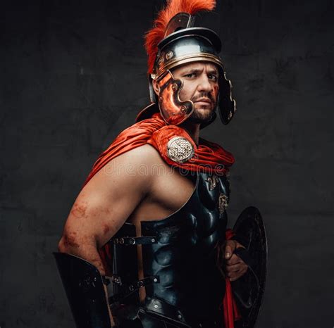 Roman Guardian Poses With Sword Near His Face In Dark Background Stock