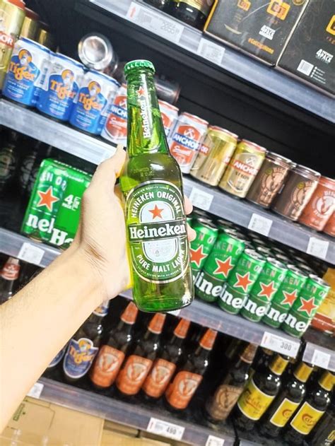 A Person Is Holding Up A Beer In Front Of Some Shelves