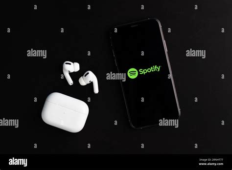 Spotify Logo Displayed On Phone Screen With Airpods Pro On The Desk