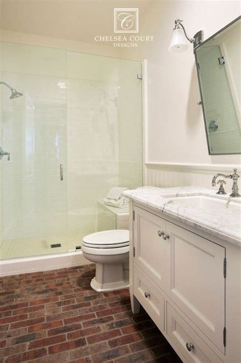 a bathroom with brick flooring and white walls, along with a walk in shower