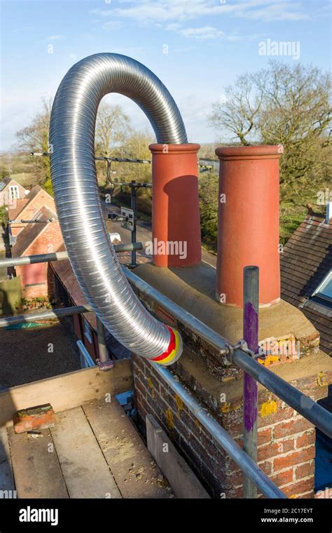 Installing A Flexible Steel Flue Liner Into A Chimney During A Wood