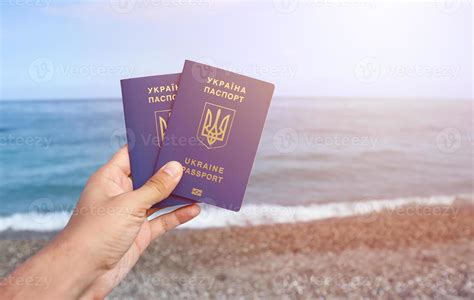 Two Biometrical Ukrainian Passports In Hand On Sea Shore Background