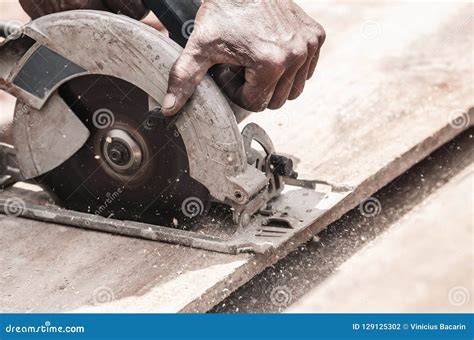 Hand Of A Carpenter Using A Circular Saw To Cut A Wooden Plank Stock