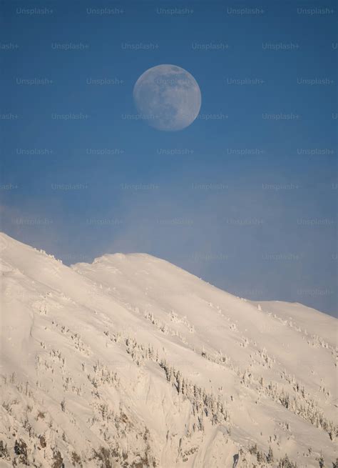 A full moon rising over a snowy mountain photo – Winter Image on Unsplash