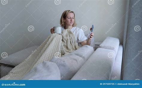 A Young Woman Drinks Hot Tea While Lying On The Sofa A Woman On The