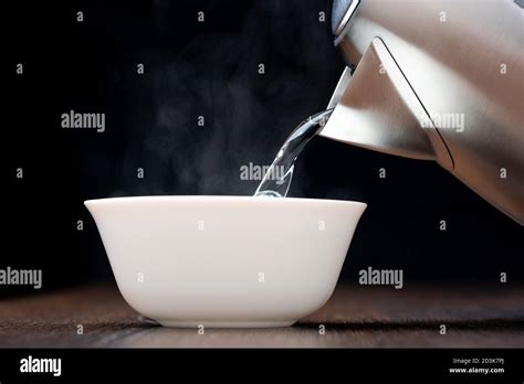 Pouring Hot Boiling Water Into A White Bowl Steam On A Dark Background Stock Photo Alamy