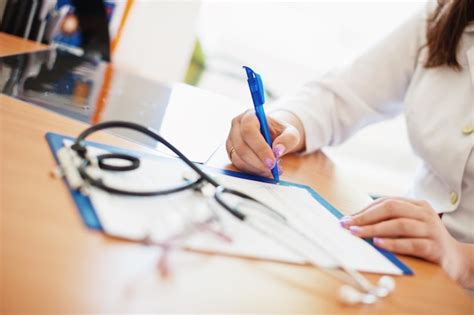 Premium Photo Midsection Of Doctor Writing On Paper At Desk