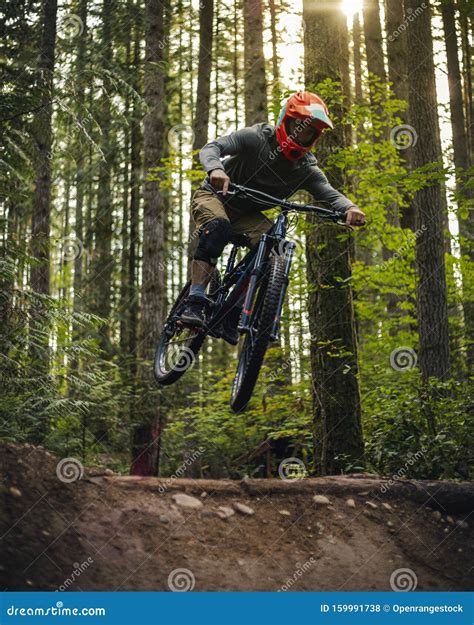 Mountain Bike Dirt Jump Action Shot Mid Air With Forest Background