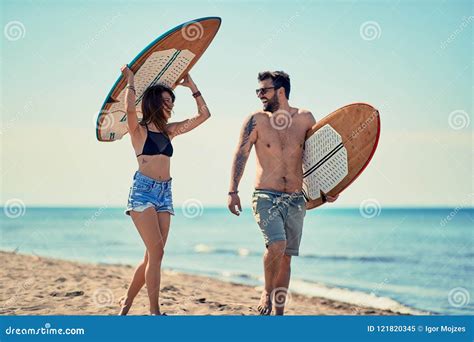 Surfers At The Beach Young Couple Of Surfers Walking On The Beach And