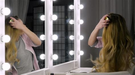 Blonde Woman Combing Her Hair In Front Of Mirror With Hair Brush Stock