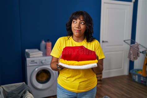 Hispanic Woman Holding Clean Laundry Smiling Looking To The Side And