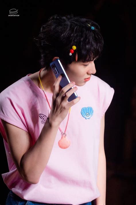 A Woman Holding A Cell Phone Up To Her Ear And Wearing A Pink T Shirt