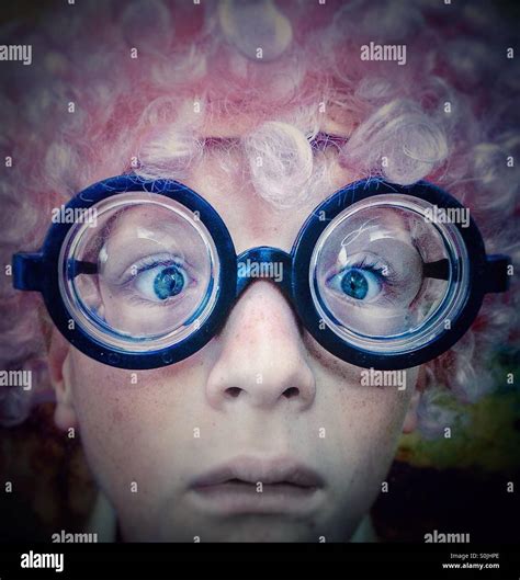 Portrait of a boy with pink wig and nerd eyes glasses looking at the ...