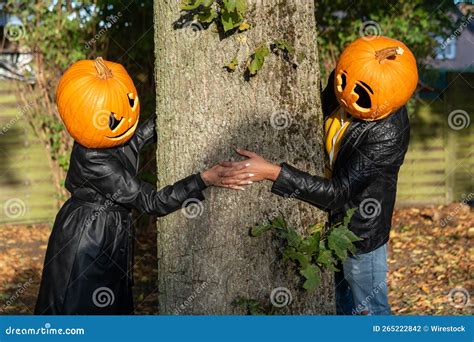 Closeup Shot Of A Couple Wearing Pumpkin Heads In The Forest Stock