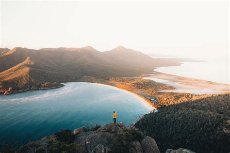 Person Standing On Hill Facing Body Of Water And Mountain During