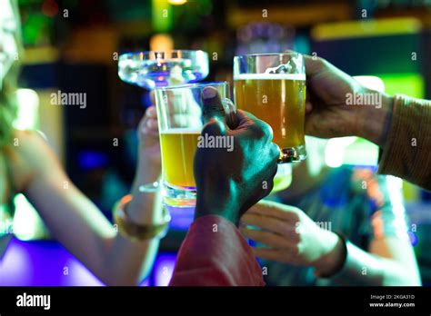 Four Diverse Male And Female Friends Drinking And And Making A Toast At The Bar In A Nightclub