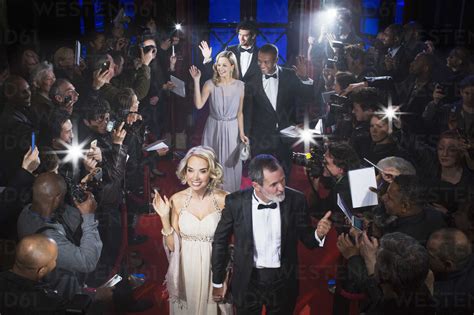 Well dressed celebrities waving to paparazzi on red carpet stock photo