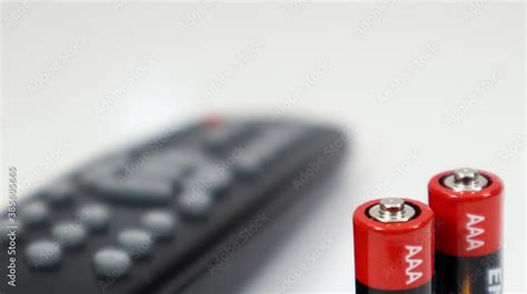 Black TV remote control with AAA alkaline batteries in red and white on a white background ...