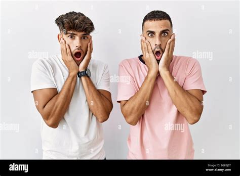 Jeune couple gay debout sur fond isolé peur et choqué surprise et expression stupéfaite avec