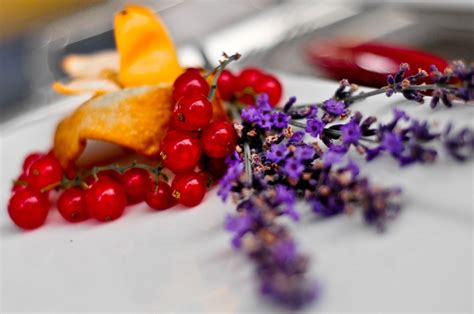 Some Berries And Other Flowers On A White Plate With Silverware In The