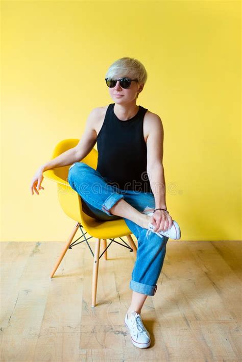 Portrait De La Jeune Femme Blonde L Gante S Asseyant Sur La Chaise Jaune Sur Le Backgrou Jaune