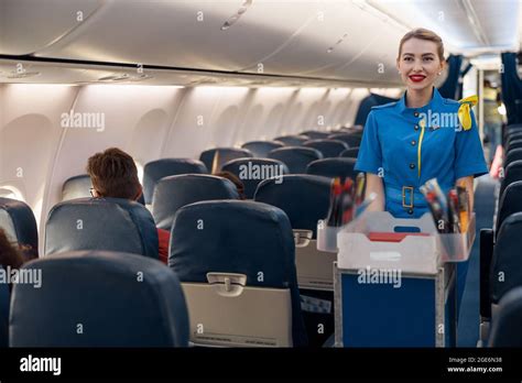 Smiling Stewardess Serving Food To Passengers On Aircraft Air Hostess