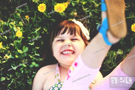 Smiling girl playing in grass with flowers, Stock Photo, Picture And Royalty Free Image. Pic ...