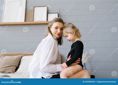 Mom And Her Daughter Cuddling Together While Sitting On Bed Stock Image