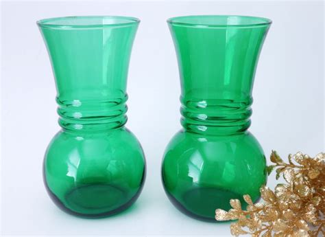 Two Green Glass Vases Sitting Next To Each Other