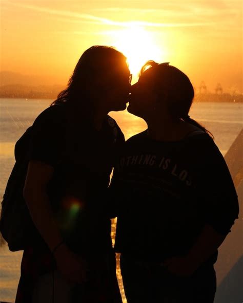 Una Pareja De Siluetas Bes Ndose En La Playa Contra El Cielo Naranja