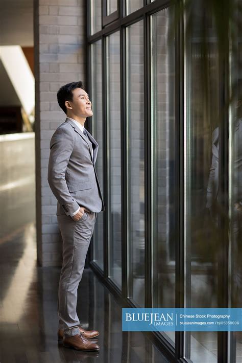 Confident Chinese Businessman Looking Through Window High Res Stock