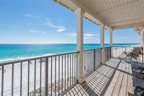 a balcony with chairs and tables overlooking the beach