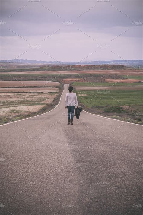 Woman walking alone in a road ~ People Photos ~ Creative Market