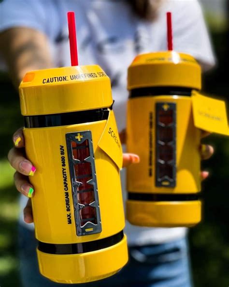 Two People Holding Yellow Cups With Red Straws In Their Hands And One