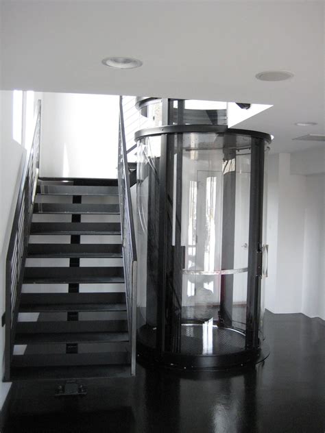 Wrap around staircase with black Vuelift round // Glass elevator // House Elevator // Elevator ...