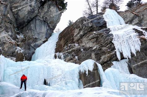 Male Ice Climber Rappelling Off A Steep Frozen Waterfall In Winter In