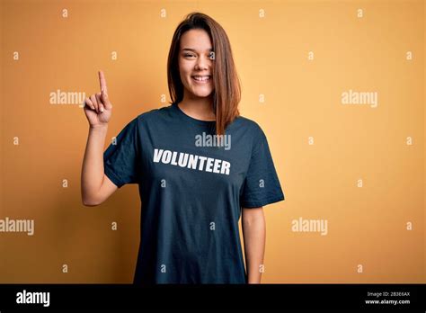 Jeune fille brunette belle faisant du bénévolat porter un t shirt avec mot de message volontaire
