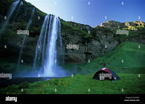 Iceland. Seljalandsfoss. Woman lying in tent reading book ...