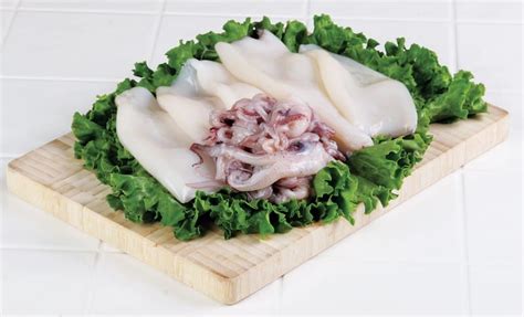 Raw Calamari over Greens on Wooden Board - Prepared Food Photos, Inc.