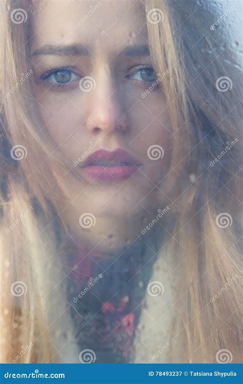 Beautiful Sad Girl With Big Eyes In A Coat Is Behind Wet Glass Stock