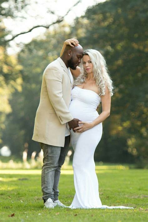 A Man And Woman Standing Next To Each Other In The Grass