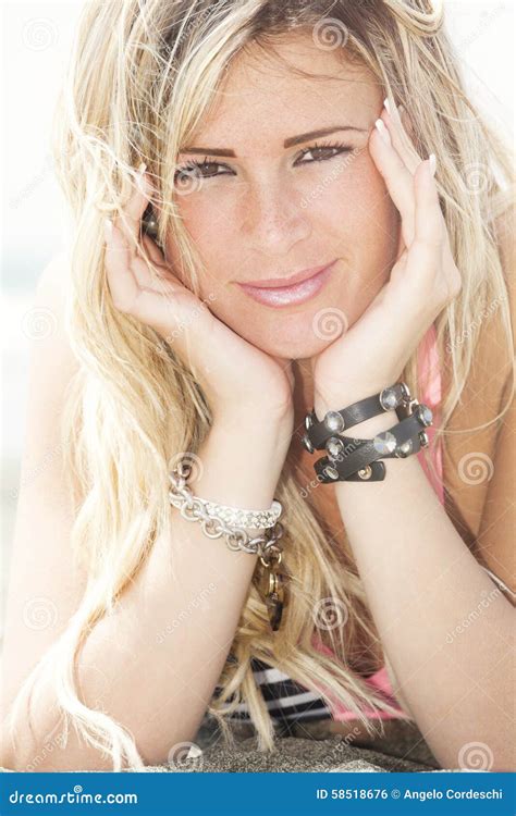 Fille Heureuse Blonde De Sourire En Mer Se Trouvant Sur La Plage Deux Mains Sous Son Visage