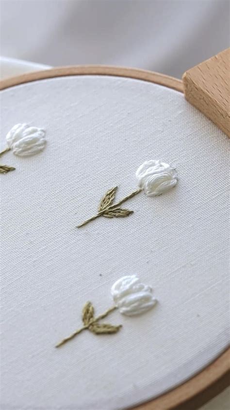 Three White Flowers Sitting On Top Of A Table Next To A Piece Of Wood