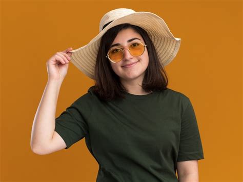 Feliz joven bastante caucásica en gafas de sol y con sombrero de playa